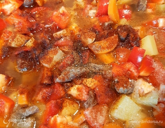 Болгарский перец и помидор нарезаем, добавляем в сковороду. Перемешиваем все хорошо и добавляем специи: соль, черный молотый перец и паприку. На этом же этапе добавляем измельченный чеснок. Убавляем огонь ниже среднего и тушим до полной готовности.