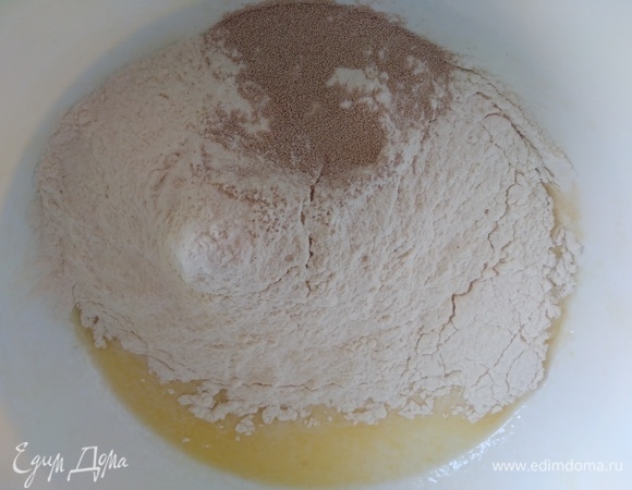 Просеять муку, смешать с дрожжами и всыпать в миску.