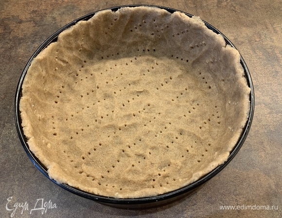Достаньте тесто из холодильника и утрамбуйте в форму, сформировав дно и бортики (у меня разъемная форма из диаметром 21 см, толщина основы получилась 5 мм). Чтобы тесто не поднялось в духовке, «потыкайте» его насквозь вилкой (бортики тоже).