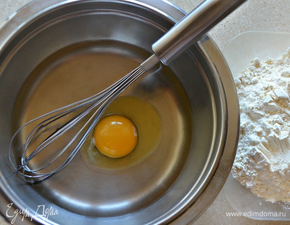 Далее займемся тестом. В емкости для замешивания взбейте яйцо, добавьте пару щепоток соли, влейте 200 мл теплой воды, перемешайте. Затем постепенно добавляйте муку. Муки может уйти чуть больше или меньше, чем указано в рецепте. Готовое тесто должно быть достаточно упругим, но эластичным. Соберите его в шар, накройте полотенцем и дайте отдохнуть 20 минут. Перед тем как начнете с ним работать, еще раз вымешайте.