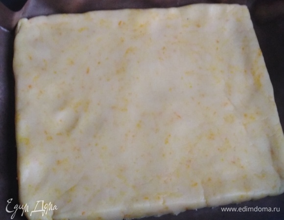 Форму застелить пергаментом. Выложить тесто. Раскатать в пласт. Поставить в разогретую до 190°C  духовку на 10 минут.