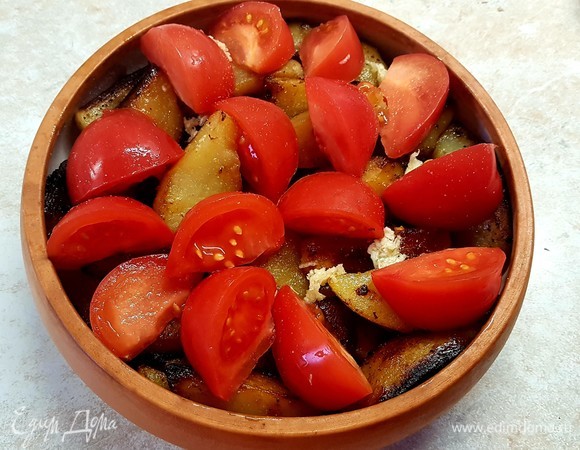 Помидоры нарезать крупными дольками и выложить сверху картофеля. Запекать в духовке 20 минут при 200°C.