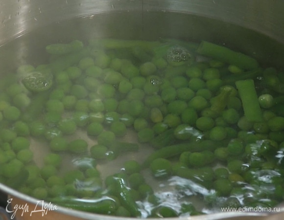 Стручковую фасоль и зеленый горошек разморозить, затем выложить в кастрюлю с кипящей водой, через несколько минут добавить спаржу и варить все еще несколько минут.