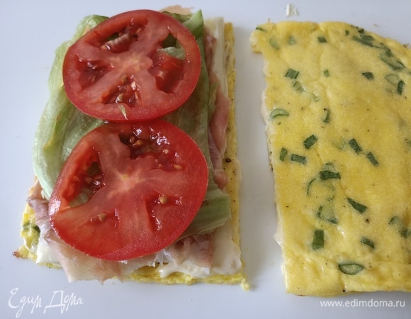 Сверху выложить сыр пластинками, ветчину, лист салата и помидор. Накрыть второй частью омлета. Разрезать.