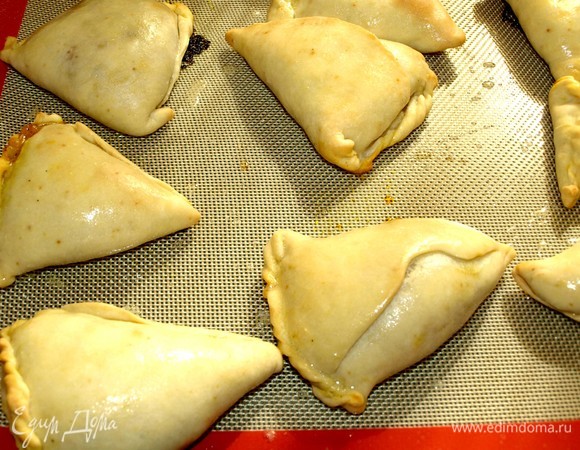 Отправляем в заранее разогретую до 180°C духовку на 30 минут. Достать готовые самосы и смазать растопленным сливочным маслом. Накрыть полотенцем и дать постоять 10 минут.