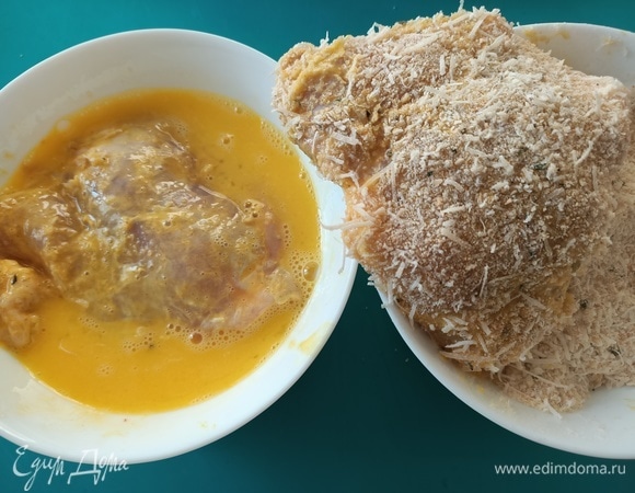 Яйца слегка взбить с помощью вилки. Обмакнуть куриные бедра сначала в яйце, затем — в сырной панировке.