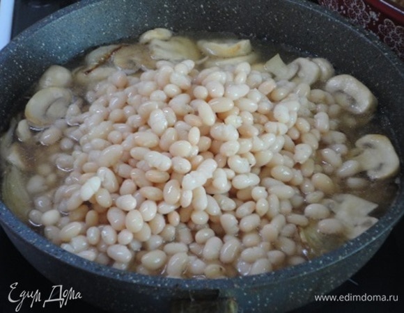 В сковороду переложить фасоль, хорошо все перемешать. Фасоль с грибами выложить в жароупорную посуду между голеней. Вставить форму с фасолью и голенями в разогретую до 180°C духовку на 25–30 минут и готовить до готовности.