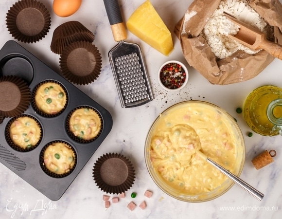 Колбасу нарезать мелким кубиком, сыр натереть на крупной терке, горошек разморозить. Добавить все в тесто и перемешать до однородности. Духовку разогреть до 170°C. Формы для кексов смазать маслом или поместить в них бумажные формочки. Заполнить тестом на 2/3.