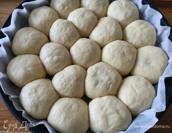 Выложить получившиеся шарики в форму швом вниз. Один — в центре, остальные — по кругу. Накрыть пищевой пленкой и дать подняться в течение 20–30 минут.