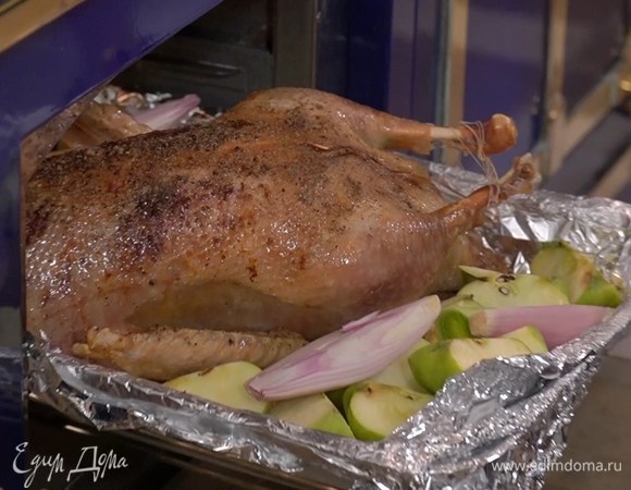 Выложить нарезанные яблоки и лук на противень рядом с гусем, посолить и поперчить их и отправить все в духовку еще на 30 минут, затем удалить фольгу и запекать гуся еще около получаса до готовности.
