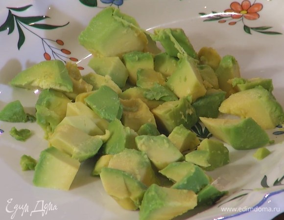 Авокадо почистить и, удалив косточку, нарезать небольшими кусочками, затем разложить на большом блюде.