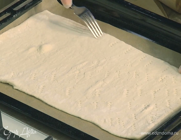 Тесто раскатать не слишком тонко, выложить на застеленный бумагой для выпечки противень и часто наколоть вилкой.