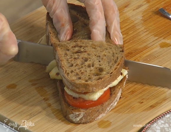 Второй кусок хлеба смазать пастой харисса и полить оливковым маслом, затем накрыть им бутерброд, сильно прижать и разрезать пополам. 
