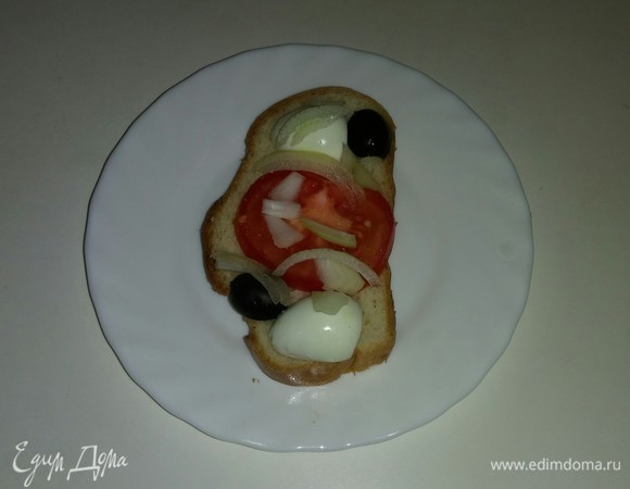 На каждый кусочек белого хлеба кладем кружок помидора, две половинки перепелиного яйца, нарезанные маслины и полоски репчатого лука.