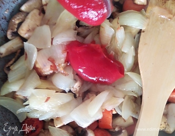 К грибам с морковкой добавить лук и томатную пасту, посолить.