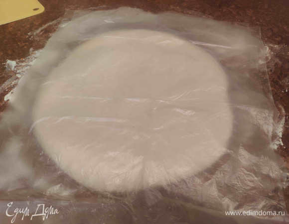 Начинаем формировать батон. Подпылим рабочую поверхность мукой совсем немного. Выложим тесто и раскатаем его в прямоугольник. Не тонко. Если чувствуете, что тесто не хочет раскатываться и «пружинит», то оставьте его отдохнуть минут на 5, накрыв пленкой от пересыхания. Оно станет более податливым.