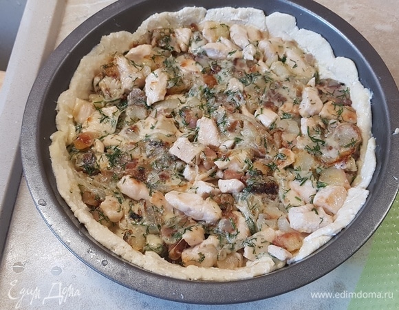 Достать тесто из холодильника и разделить на две неравные части. Большую часть раскатать в круг и выложить в форму для выпекания, сформировать бортики. Выложить начинку и немного ее утрамбовать.