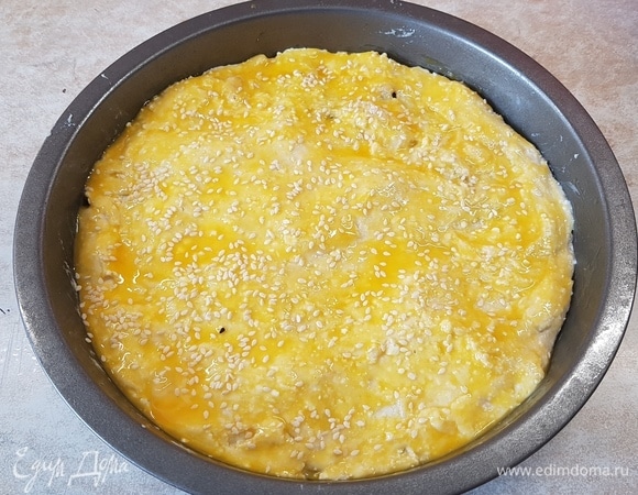 Вторую часть теста раскатать в круг и накрыть им пирог. Защипнуть края. Смазать верх желтком и посыпать кунжутом. Выпекать при 180°C 40 минут.