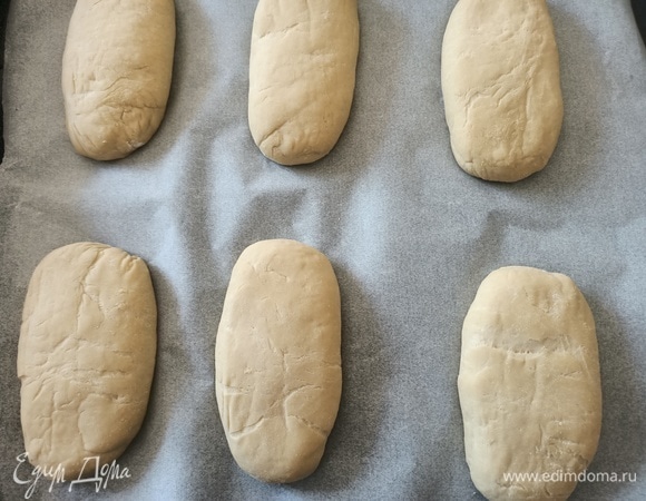 Противень застелить пергаментной бумагой. Вытянуть каждый шар в длину и переложить на противень. Накрыть и дать тесту подняться в течение часа.