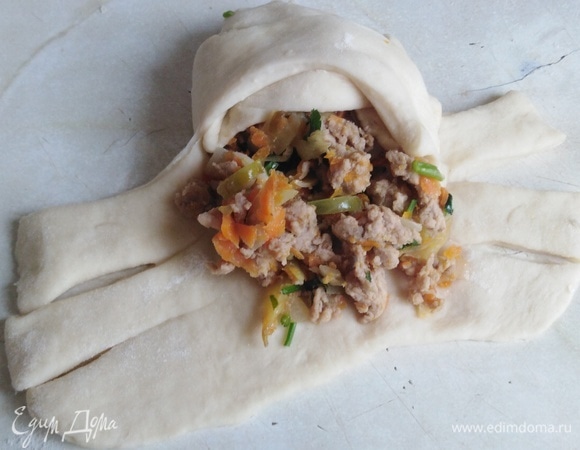 Каждую часть раскатать в прямоугольный пласт. На середину выложить 2 ст. л. начинки. Края теста нарезать пластинами. Перекрещивая их, сформировать кулебяку.