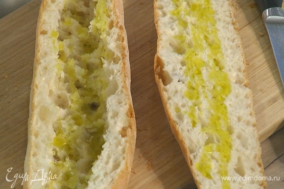 Багет разрезать вдоль пополам, из нижней части вынуть мякиш, затем обе половинки сбрызнуть внутри оливковым маслом.