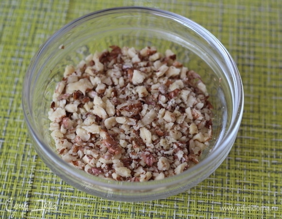 Грецкий орех измельчить. Я люблю крупные кусочки, поэтому измельчаю скалкой. Можно перемолоть в мелкую крошку в измельчителе.