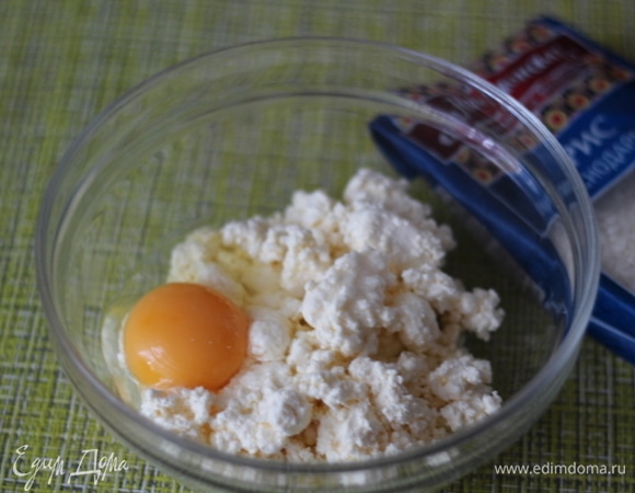 В творог добавляем яйцо, ванилин и хорошо разминаем ложкой до однородной массы. Изюм запарить кипятком, слить воду и обсушить салфеткой.