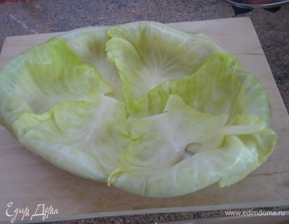 У капусты надрезать кочерыжку по кругу и опустить в кипящую воду на несколько минут. Осторожно снять верхние мягкие листья. Затем снова опустить капусту в кипящую воду и снять следующий слой листьев. Форму для запекания (если круглая, то примерно 24 см в диаметре) смажьте сливочным маслом и сразу выстилайте листьями по кругу так, чтобы тонкая часть листьев свисала по краям. И по центру выложите несколько листьев, чтобы все дно было закрыто. Оставьте еще несколько листьев, чтобы застелить все дно, а оставшуюся капусту порубите для начинки.