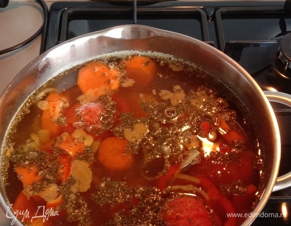Начинаем поэтапно добавлять крупно нарезанные овощи в кастрюлю с интервалом в 10 минут. Порядок добавления: картофель, морковь, перец, помидоры без кожицы с чесноком и перцем чили вместе. Доводим до кипения, убавляем огонь на минимальный и варим под крышкой в течение 1,35 часа. Примерно за 40 минут до готовности добавляем специи в произвольном порядке.