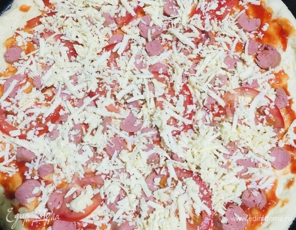 Тесто раскатать, положить на смазанный маслом противень, смазать кетчупом, нарезать сосиски, помидоры и положить начинку слоями.