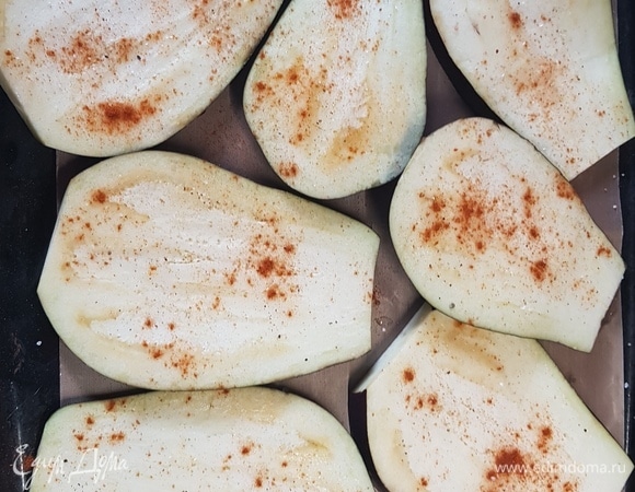 Баклажаны нарезать слайсами. Выложить на противень, застеленный бумагой. Смазать каждую пластинку баклажана оливковым маслом, посыпать солью, поперчить. Я еще добавила копченую паприку. Поставить в духовку запекаться при температуре 200°C на 30 минут.