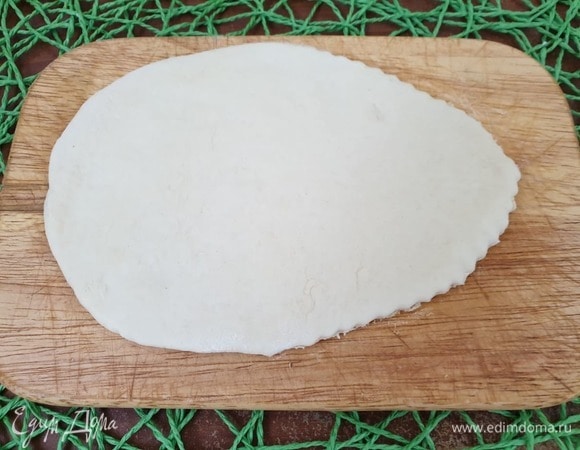 Подошедшее тесто разделим на заготовки. Заготовку раскатываем в форме овала. Немного подрезаем с одной стороны, как показано на фото.