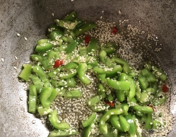 В казане с толстым дном нагреваем масло, добавляем перцы и кунжут, обжариваем.