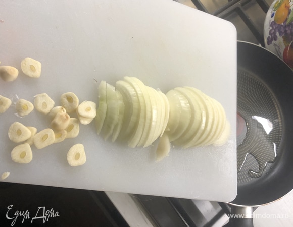 Чеснок режем вдоль, лук — полукольцами, отправляем в разогретую сковороду с маслом.