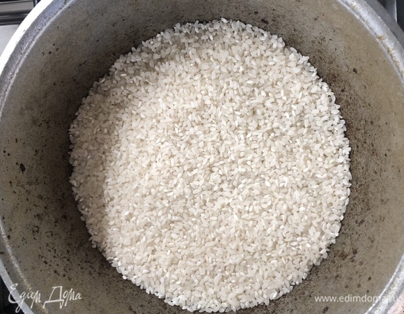 К хорошо обжаренной говядине добавляем содержимое сковороды, засыпаем рисом, далее можем добавлять специи, которые есть под рукой. Я посолил, поперчил, добавил целый кайенский перец и головку чеснока (но можно расширить набор специй: куркума, зира, шафран, кумин, барбарис, паприка, чабер и много других). Заливаем рис на два пальца водой и накрываем крышкой, после закипания убавляем огонь.