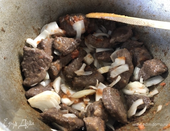 Сперва жарим говядину на оливковом масле, постоянно помешивая. Когда мясо начнет поджариваться, добавить лук, чеснок, через минуту-две — столовую ложку томатной пасты, перемешать.