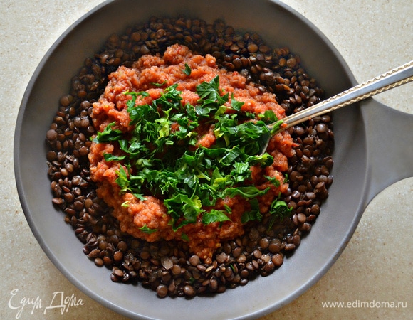 Готовую чечевицу поместите в сковороду или сотейник, добавьте овощной соус и рубленую петрушку. Если вы любите кинзу, поместите ее к соусу вместо петрушки, она очень хорошо сюда подойдет. Перемешайте, доведите до кипения и протушите на слабом огне около 7 минут.