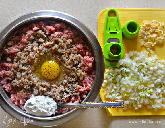 Готовую гречку добавьте в фарш, туда же вбейте 1 крупное яйцо, добавьте 1 ст. л. крахмала, посолите и поперчите, приправьте специями. Лук мелко порубите, чеснок пропустите через пресс и также добавьте в фарш.