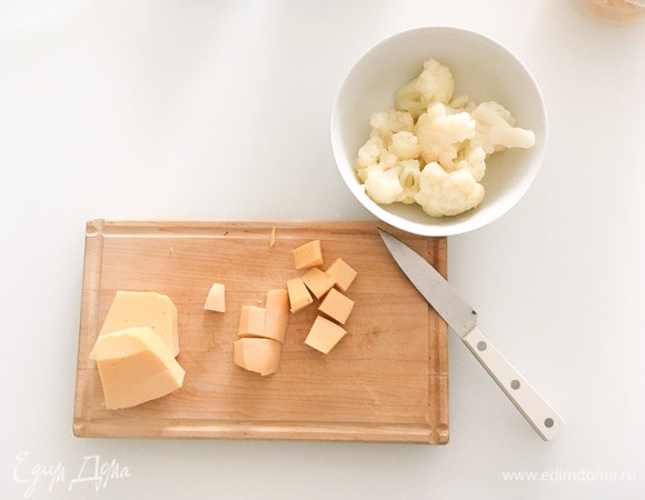 Отварить цветную капусту в подсоленной воде (ориентировочно 10 минут). Мелко нарезать лук, чеснок, обжарить их на сковороде на оливковом масле. Нарезать кубиками сыр.