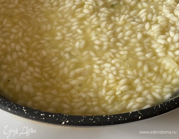 Когда вино выпарится, небольшими порциями начинаем добавлять в рис овощной бульон. Готовим до почти полной готовности риса.