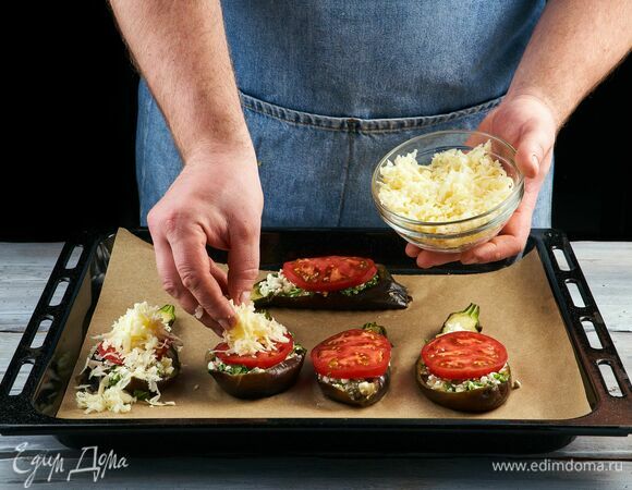 Начините полученным фаршем баклажанную кожицу. Выложите сверху нарезанные слайсами помидоры и посыпьте тертым сыром.<br />
Запекайте в разогретой до 180°C духовке 10 минут до зарумянивания сыра.