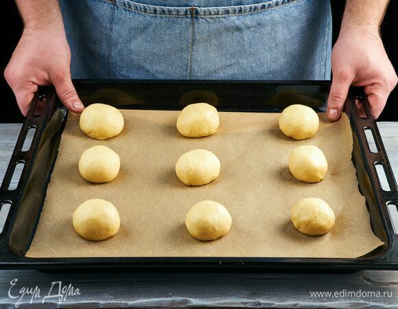 Сформируйте круглые булочки и выложите на противень, покрытый пергаментной бумагой. Накройте полотенцем и поставьте в теплое место на 30 минут для дальнейшей расстойки.
