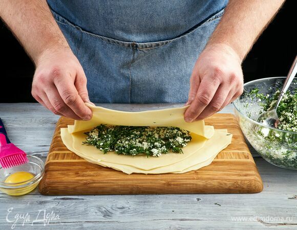 Смажьте один край желтком, чтобы лучше склеивалось. Сложите полумесяцем кутаб, обрежьте лишнее.