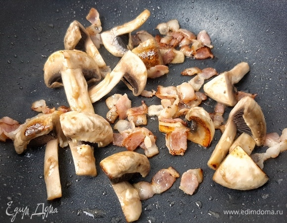 Бекон нарезаем полосками, шампиньоны — на четверти. Обжариваем быстро на сильном огне с добавлением капли растительного масла. Перекладываем в тарелку, сковороду оставляем.