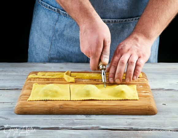 Скрепите края, а затем ножом разрежьте тесто на квадратики с начинкой посередине.<br />
Выложите равиоли в кипящую подсоленную воду и отварите до готовности.