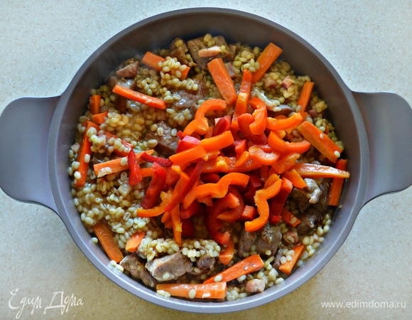 В сотейник добавьте морковь, тушите блюдо в течение 7 мин. Далее добавьте перец и тушите еще в течение 5 мин.