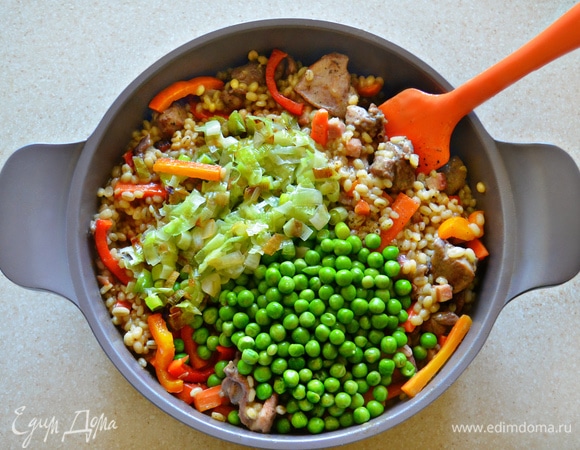 На отдельной сковороде обжарьте на оливковом масле лук-порей и вместе с зеленым горошком добавьте в сотейник. Посолите, поперчите и тушите в течение 15 мин. Периодически необходимо аккуратно перемешивать блюдо. При необходимости добавьте еще немного бульона. Овощи должны полностью приготовиться.