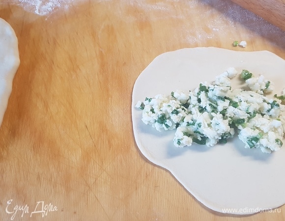 Тесто разделить на несколько частей. Каждую часть раскатать, выложить на нее столовую ложку брынзы. Защипать и раскатать настолько тонко, насколько это возможно. 