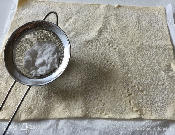 Слоеное тесто немного раскатать, разрезать пополам, наколоть вилкой, посыпать сахарной пудрой и выпекать в разогретой до 180°C духовке в течение 10–15 минут.