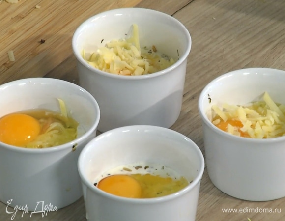 В каждую форму разбить по яйцу, так чтобы желток не растекся, посыпать оставшимся сыром.